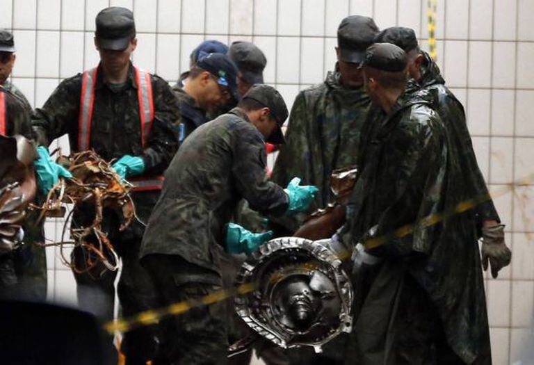 Membro das Forças Armadas recolhem pedaços do avião.