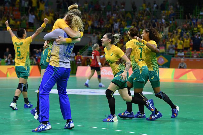A equipe feminina de handebol comemora a vitória.