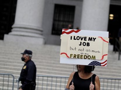 Mulher segura placa que diz que ela ama seu trabalho, mas não tanto como sua liberdade, em protesto em Nova York.