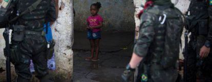Garota observa rapaz é interrogado por soldados do Exército na Vila Kennedy, no Rio.