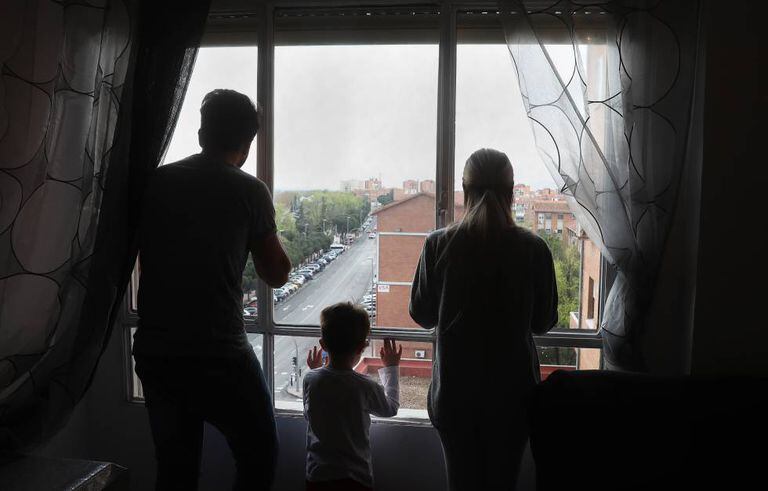 Miguel, Dara e seu filho olham pela janela do apartamento que ocupam.