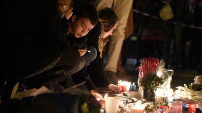 Um grupo de pessoas, entre elas um menino, colocam flores e velas nas proximidades da sala Bataclan, em Paris, um dos cenários dos ataques jihadistas cometidos na noite de 13 de novembro de 2015.