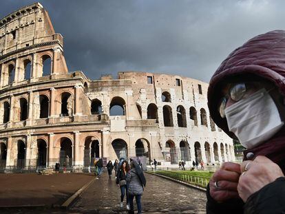 Um homem com máscara diante do Coliseu, em Roma.