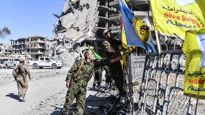 Membros das Forças Sírias Democráticas colocam sua bandeira na praça A o-Naim em Raqa nesta terça-feira.