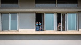 Um grupo de mulheres com máscaras olha do Hospital Jinjiantang, em Wuhan.