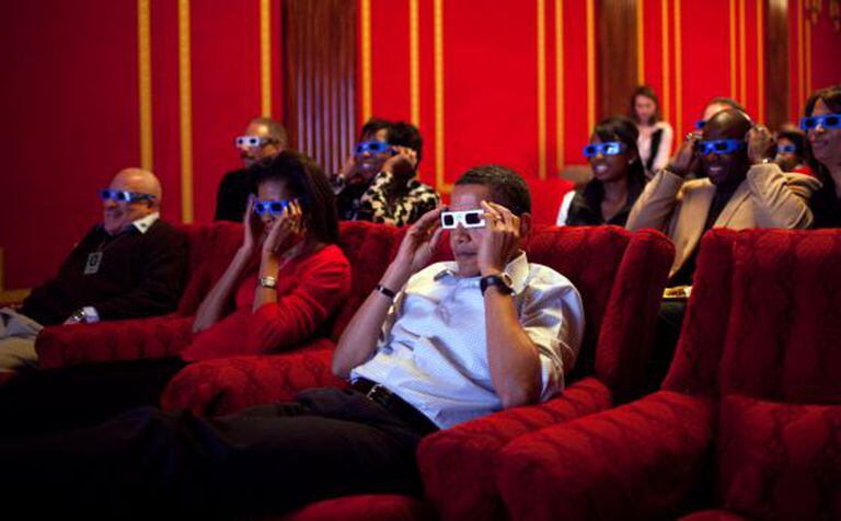 Os Obama assistem um anúncio em 3D na sala de cinema da Casa Branca.