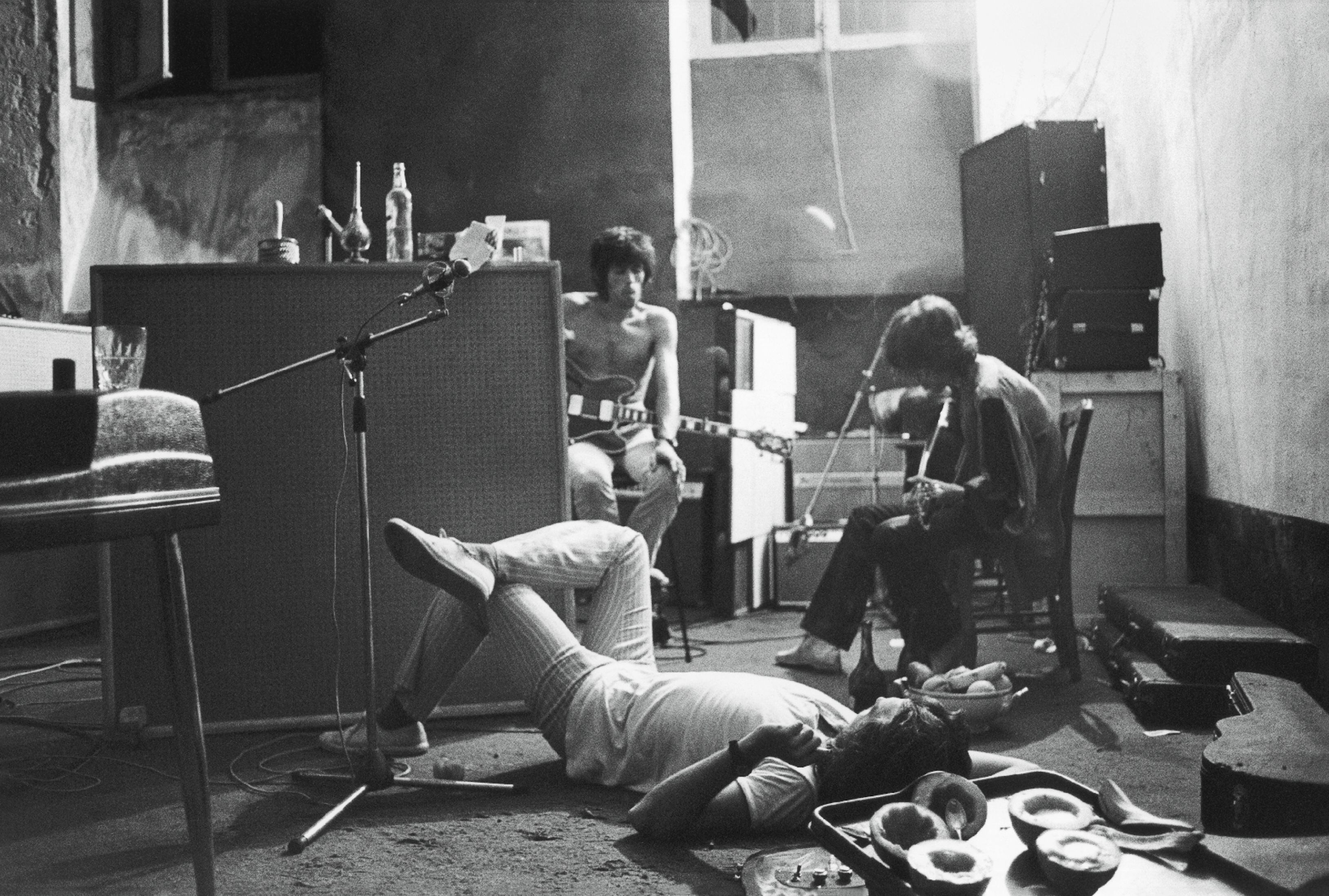 Jimmy Miller (no chão), Keith Richards (esquerda) e Mick Jagger (direita) nas tocas da Villa Nellcote, 1971.