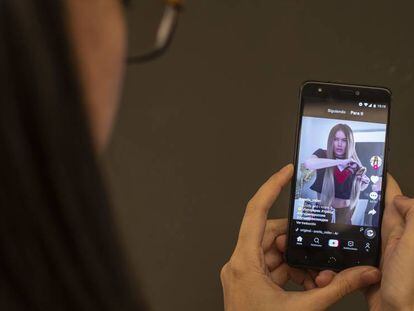 Uma mulher assiste a um vídeo no TikTok. No vídeo, o trailer do app.