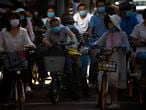 People wearing face masks to protect against the coronavirus wait to cross an intersection in the central business district in Beijing, Wednesday, July 15, 2020. China is further easing restrictions on domestic tourism after reporting no new local cases of COVID-19 in nine days. (AP Photo/Mark Schiefelbein)