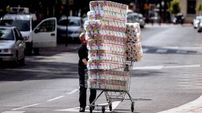Um repositor empurra um carrinho com papel higiênico até uma loja em Málaga.