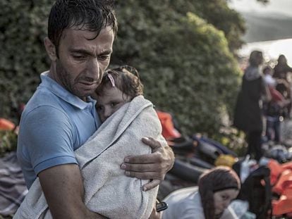 Um homem abraça e seca sua filha ao desembarcarem na ilha de Lesbos, após atravessarem parte do mar Egeu num bote de plástico.