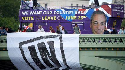 Um ônibus com propaganda em favor da saída da UE passa por trás de partidários da permanência.