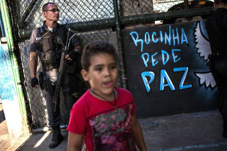 Uma criança e um policial na quadra onde moradores da Rocinha pediram à volta da sua rotina.