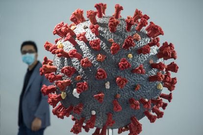 Um homem passa diante de um modelo do vírus SARS-CoV-2 numa exposição sobre saúde em Wuhan, na China, o primeiro local onde o novo coronavírus foi detectado.
