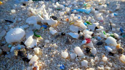 Pequenos fragmentos de plástico, dispersos entre na da praia.