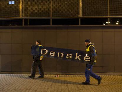 Dois operários retiram o cartaz do Danske Bank na filial de Tallin (Estônia), em 5 de outubro de 2019.