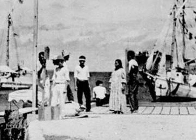 No centro do grupo no cais está a figura que o History Channel afirma que poderia ser Amelia Earhart. À esquerda, ao lado do poste, o suposto Noonan.