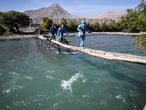 Health workers cross the Camana River to inoculate elderly citizens with doses of the Pfizer-BioNTech vaccine against COVID-19, in Arequipa, southern Peru, on July 2, 2021. (Photo by Diego Ramos / AFP)
