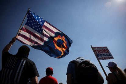 Um partidário do presidente Donald Trump ergue uma bandeira com referência ao movimento extremista QAnon, durante manifestação este ano.