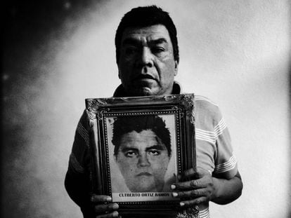 Oscar Ortiz Serafin segura a foto de seu filho Cutberto Ortiz Ramos em uma sala de aula transformada em dormitório para as famílias dos alunos desaparecidos da Escola Rural de Ayotzinapa.