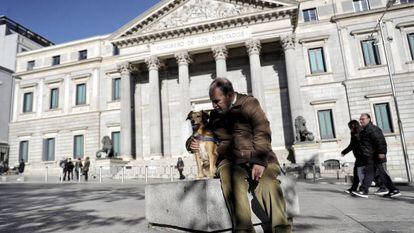 Cão passeia com seu dono em frente ao Congresso dos Deputados.