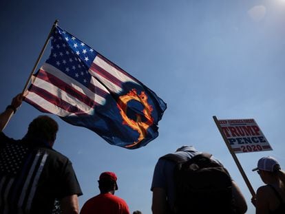 Um partidário do presidente Donald Trump ergue uma bandeira com referência ao movimento extremista QAnon, durante manifestação este ano.