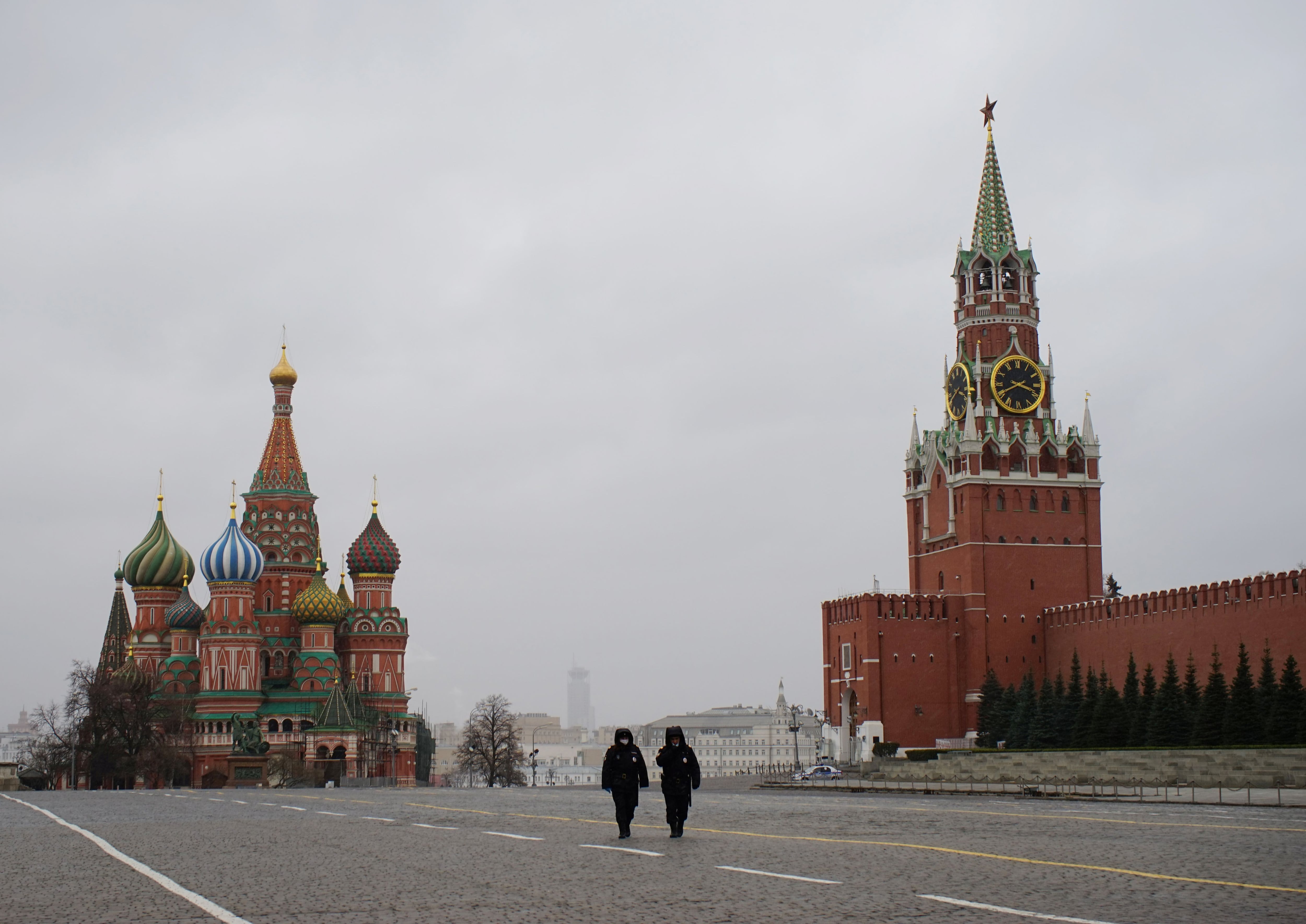 Dois policiais caminham pela praça Vermelha de Moscou, em frente à catedral de São Basílio, e o Kremlin, nesta segunda-feira, primeiro dia de quarentena na capital russa. 