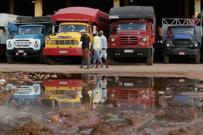 Um grupo de trabalhadores passa diante de caminhões em Havana.