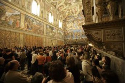 Multidão de turistas contempla os frescos de Michelangelo.