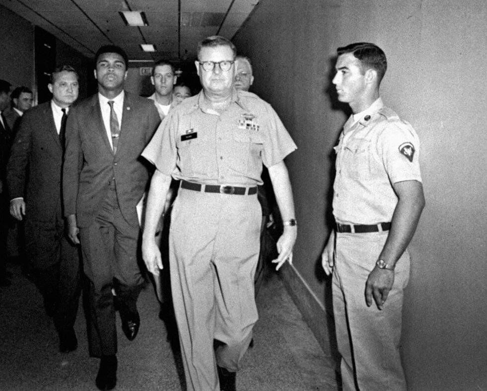 Muhammad Ali é escoltado pelo comandante do centro de recrutamento de Houston, em 1967, depois de ter se recusado a se alistar.