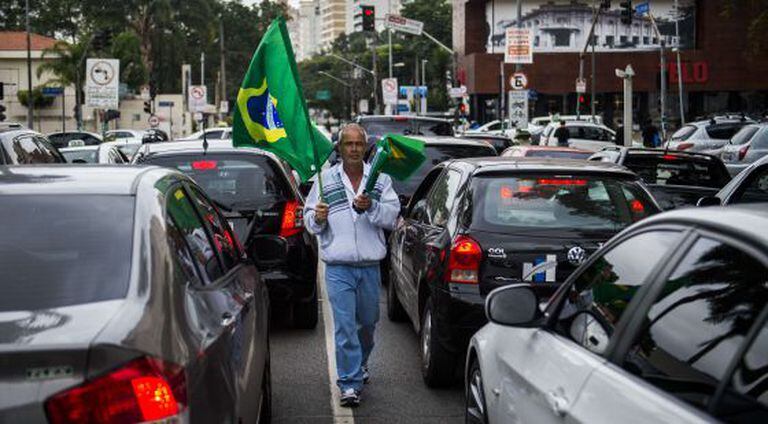 Um vendedor de bandeiras caminha entre os carros em São Paulo.