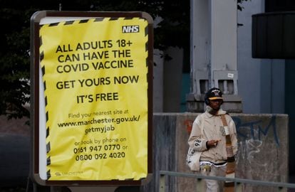 Um homem passa junto a um cartaz que estimula a população a se vacinar contra a covid-19, nesta segunda-feira, em Manchester (Reino Unido).