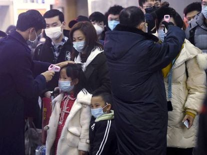 Agentes verificam temperatura de viajantes procedentes de Wuhan na estação de Hangzhou (China).
