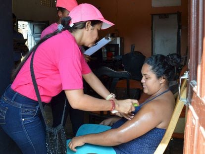 Profissionais de saúde ensinam uma mulher grávida a passar repelente contra o zika vírus em Barranquilla (Colônbia).