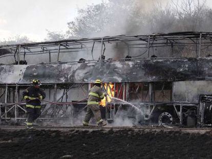 Bombeiros tentam apagar as chamas de um ônibus incendiado em Jalisco.