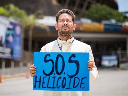 Um sacerdote sustenta um cartaz em frente à sede do Serviço de Inteligência, em Caracas.