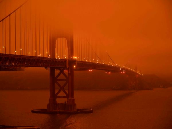TOPSHOT - Cars drive along the San Francisco Bay Bridge under an orange smoke filled sky at midday in San Francisco, California on September 9, 2020. - More than 300,000 acres are burning across the northwestern state including 35 major wildfires, with at least five towns "substantially destroyed" and mass evacuations taking place. (Photo by Harold POSTIC / AFP)