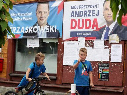Garotos em frente a cartazes dos candidatos Andrzej Duda e Rafal Trzaskowski, na cidade de Raciaz.