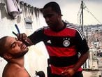 Adriano faz a barba em uma rua da Vila Cruzeiro.