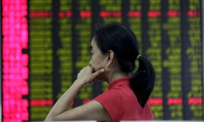 Investidora diante de um painel com os valores em Pequim.
