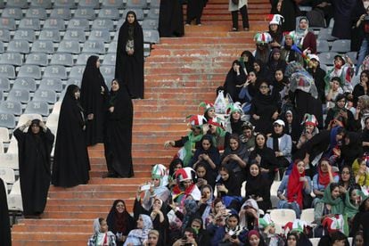 Torcedoras iranianas na grade do estádio Azadi, vigiadas por policiais.