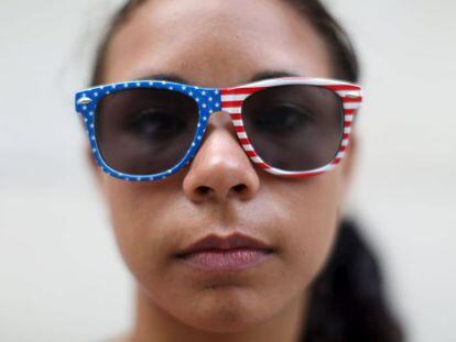 Estudante cuba posa em Havana com óculos enfeitados com a bandeira dos EUA.