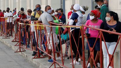Pessoas de máscara fazem fila para comprar alimentos num mercado de Havana, em fevereiro.