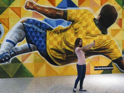 Uma garota tira uma foto em frente a painel no aeroporto de Bras&iacute;lia. 