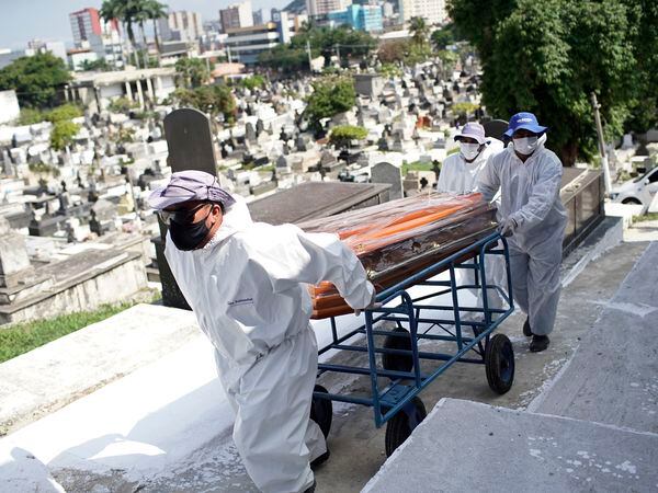 Cemetery workers carry the coffin of Genivaldo Santos, who died from Covid-19, who died from the new coronavirus, as relatives cry during his burial at the municipal cemetery in Nova Iguacu, Brazil, Wednesday, Nov. 25, 2020. Rio has seen a surge of hospitalizations due to COVID-19 infections. There has been speculation the nation could be on track to follow the path of U.S. and Europe, where new cases are spiraling. (AP Photo/Silvia Izquierdo)