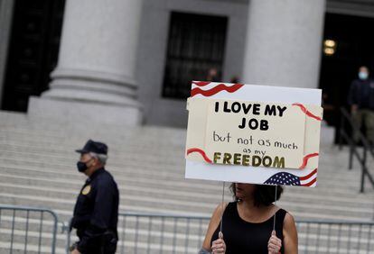 Una mujer sostiene un cartel que dice que ama su trabajo, pero no tanto como su libertad, en una protesta contra las vacunas obligatorias de la ciudad de Nueva York