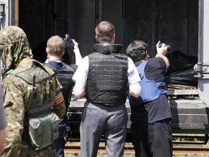 Inspetores da OSCE fotografam os corpos na estação de Torez.