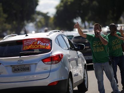 Apoidores de Bolsonaro se manifestam ao lado de carro com faixa contra o presidente, próximo ao Congresso Nacional, em Brasília, em 13 de junho.
