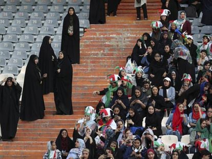 Torcedoras iranianas na grade do estádio Azadi, vigiadas por policiais.