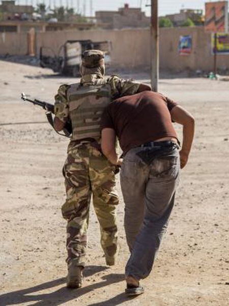 Um soldado detém um suspeito em Kerbala.